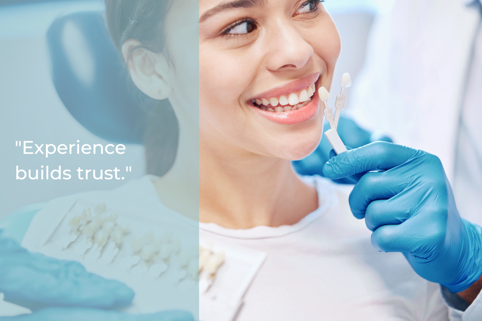 A dentist wearing blue gloves holds a tooth shade guide next to a smiling patient’s teeth; text reads "Choosing the best dentist builds trust.