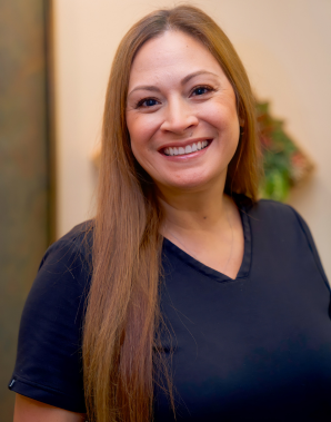 Meet the Team: A woman with long brown hair, wearing a black shirt, smiles at the camera indoors.